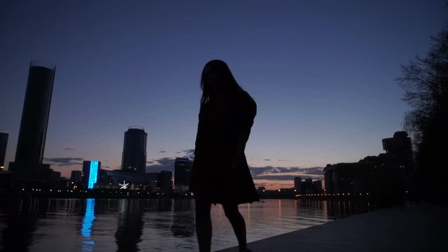 Silhouette of the girl at night on the river bank