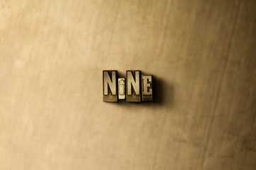 NINE - close-up of grungy vintage typeset word on metal backdrop. Royalty free stock illustration.  Can be used for online banner ads and direct mail.