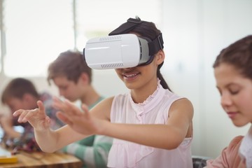 School girl sitting in classroom using virtual reality headset 