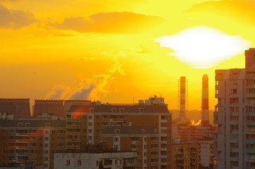 Sunset or sunrise over the city. The orange light. Pipe smoke. Nuclear power plant, heating plant