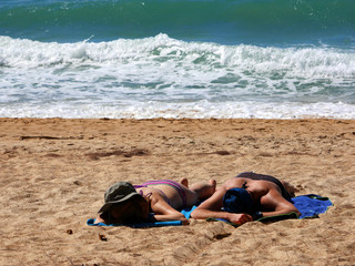 Couple sun tanning on a windy beach