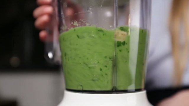 Woman blending ingredients to make green smoothie