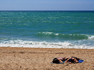 Fototapeta na wymiar Couple sun tanning on a windy beach