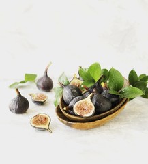 dark blue Fresh figs in a wooden bowl on a white marble table, selective focus