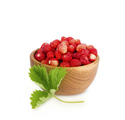 Wild small strawberries in a wooden bowl with leaves. Ripe and tasty strawberries isolated on white background. Sweet and juicy berry with copy space for text.