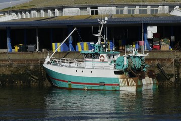 Fototapeta na wymiar White and Turquoise fishing boat moored alongside the pier at the fishing harbor of Lorient, France.