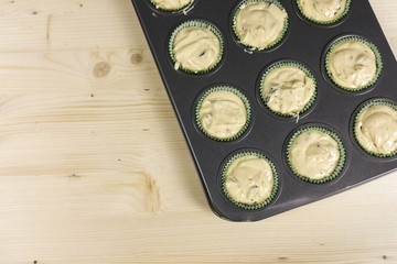 Uncooked muffin with chocolate drops on wood background - top view