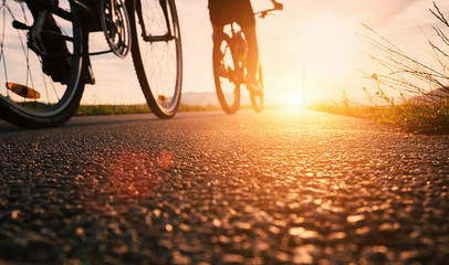 Obraz premium Bike wheels close up image on asphalt sunset road