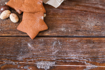 Sweet gingerbread stars on wooden background flat lay. Top view on rustic table with chocolate cookies, free space for advertisement. Menu, dessert, confectionery concept