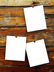 Three blank square photo frames with pins on brown wooden boards background