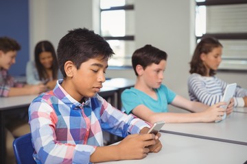 Students with digital tablet and mobile phone in classroom