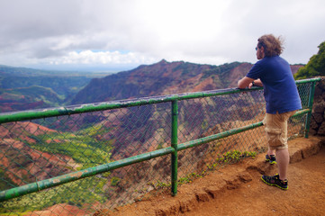 Fototapeta na wymiar Young male tourist enjoying the view into Waimea Canyon, Kauai, Hawaii