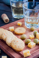 Cheese biscuits and slices of cheese on a wooden board, selective focus