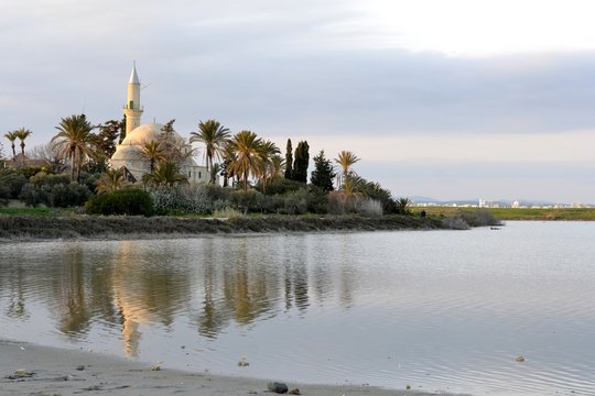 Architecture of Hala Sultan Tekken with water reflections and cloudy sky