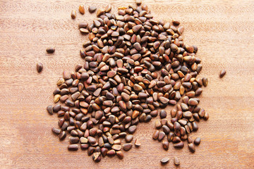 Кедровые орехи - небольшие семена сибирских кедровых сосен, разбросанных на деревянной доске.