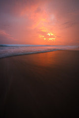 Sunset clouds and waves on empty beach