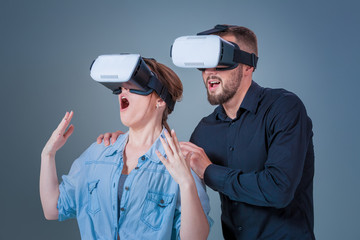 Excited young man and woman having fun with a VR glasses
