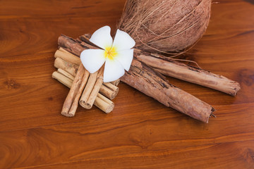 Fototapeta na wymiar Whole coconut, cinnamon sticks and flower on wooden brown table