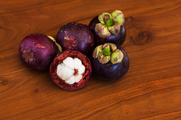 Five fresh mangosteens on wooden brown table