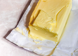 Creamy butter in its unwrapped foil paper. Isolated on light table