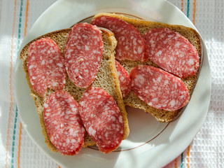 sandwiches of black bread with smoked sausage lies on a plate