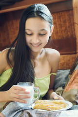 Pretty young brunette enjoying a glass of milk at home and smiling