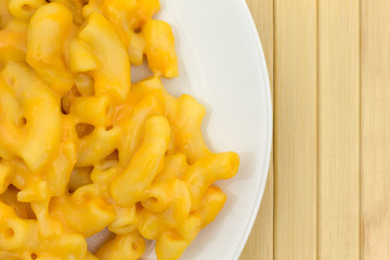 Macaroni and cheese on a plate top close view atop a wood place mat.