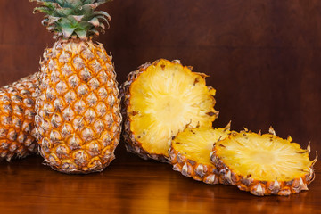 Two whole and some cutting slices pineapples on wooden table