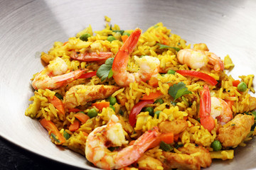 Udon stir-fry rice with shrimp and vegetables in wok pan on black burned stone background