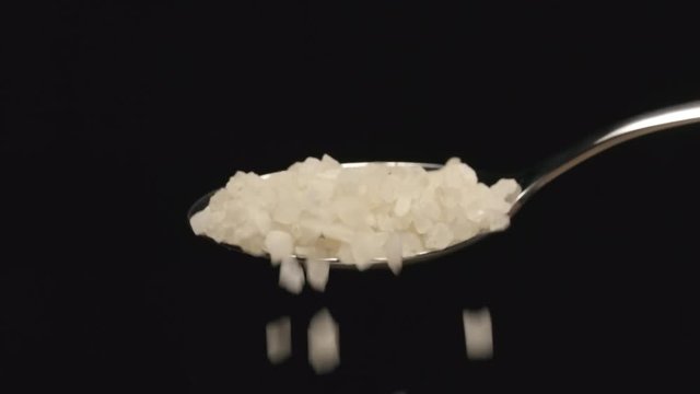 SLOW MOTION: Coarse salt falls from a spoon