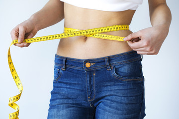 Young woman with tape measure around waist