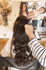 stylist working with the curling iron on a long hair