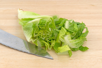 Romaine lettuce on a wood cutting board with a knife.