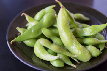 boiled green soybeans on black dish