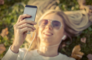 Woman listening music on grass at autumn time