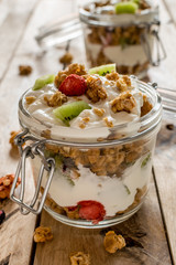 Granola and Greek yogurt in jar. Healthy snack concept. Beautiful rustic wooden background.
