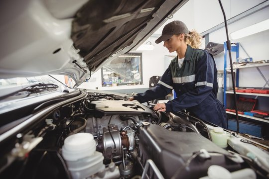 Female mechanic servicing car