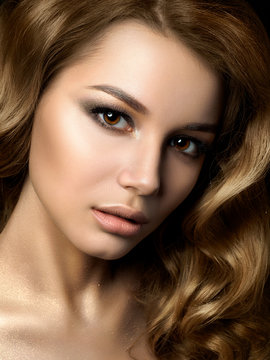 Beauty portrait of young woman with golden makeup