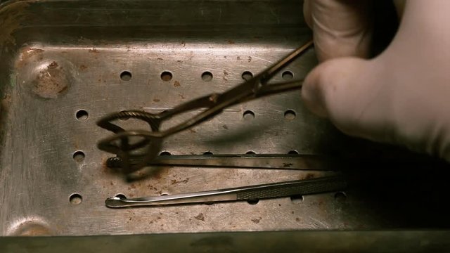Old forceps and medical scissors in steel tray. Medical equipment. Macro shot.