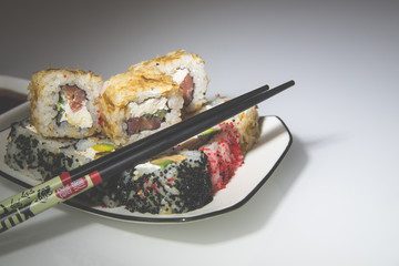 sushi and chopsticks lying on a white plate 