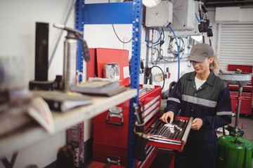 Female mechanic arranging tools in toolkit