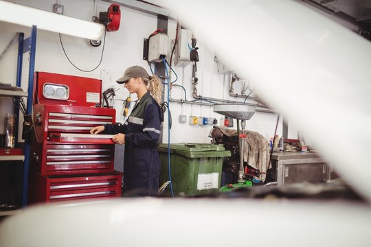 Female mechanic arranging tools in toolkit