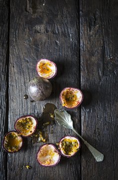 Whole and hollowed out passion fruits on a wooden surface