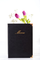 Menu and vase with flowers on white wooden table