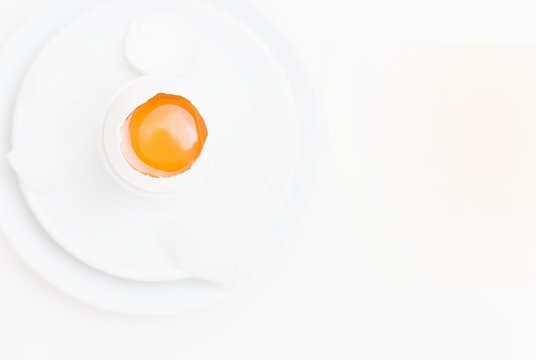 A raw egg on a white plate on a white surface