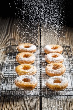 Freshly baked doughnuts being dusted with powdered sugar