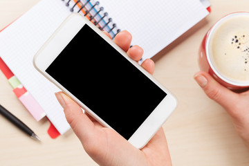 Woman holding smartphone above business desk