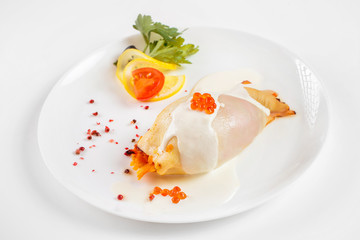 Steamed calamari filled with vegetables decorated with red caviar isolated at white background.