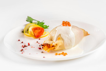 Steamed calamari filled with vegetables decorated with red caviar isolated at white background.