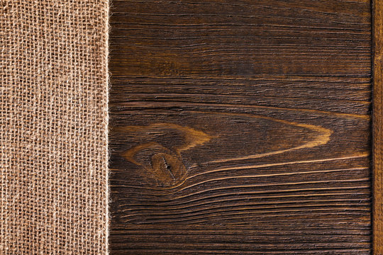 Macro image of textured hessian textile at brown wooden board background.